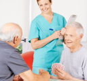 2 patients playing cards and a caregiver standing